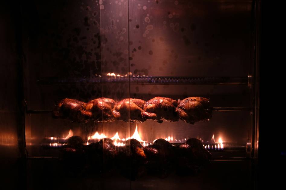 Modern rotisserie oven with golden roasted chicken on kitchen counter